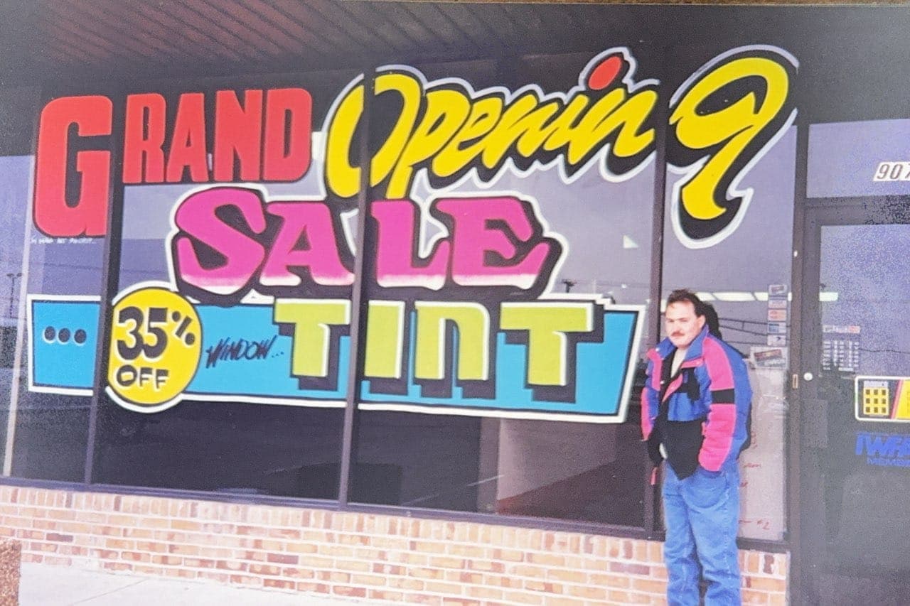 Jason Moore outside Global Tint Shop with its grand opening sale banner in the 1980s